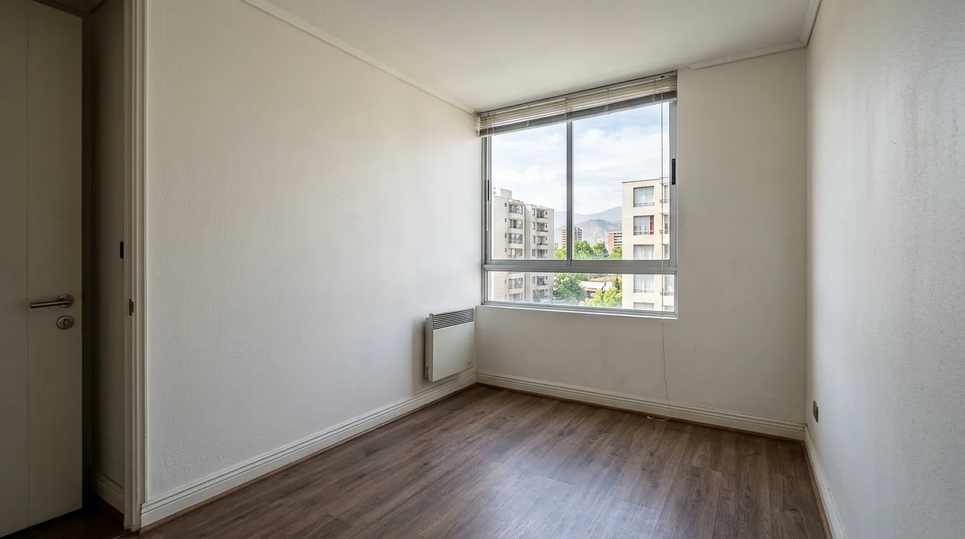 Metros útiles y metros totales: dormitorio vacío de un departamento, con ventana y radiador, antes de ser entregado.